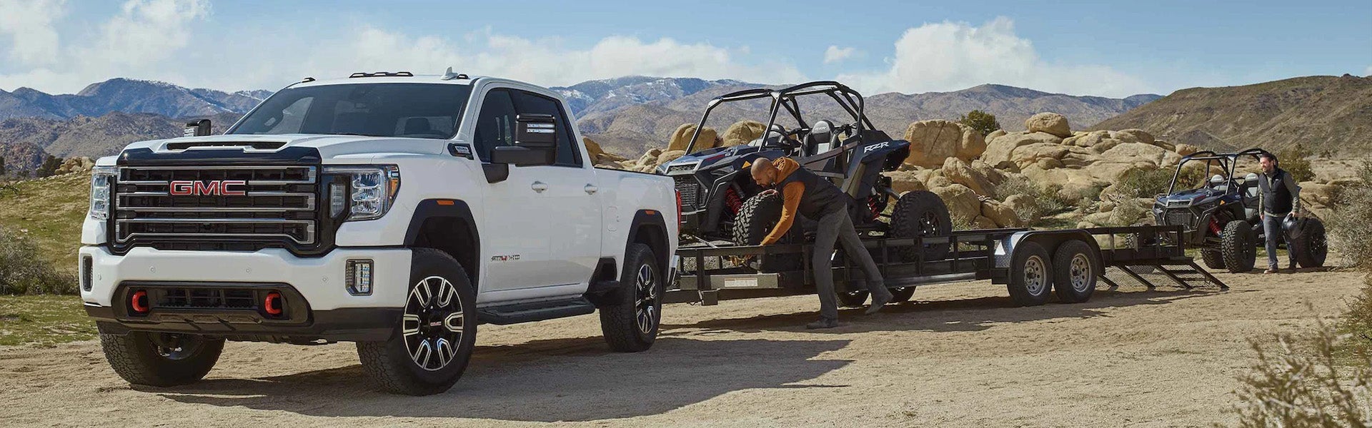 2022 GMC Sierra 2500HD towing a large trailer on a rural road.