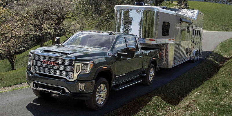 A 2022 GMC Sierra towing a horse trailer on a rural road